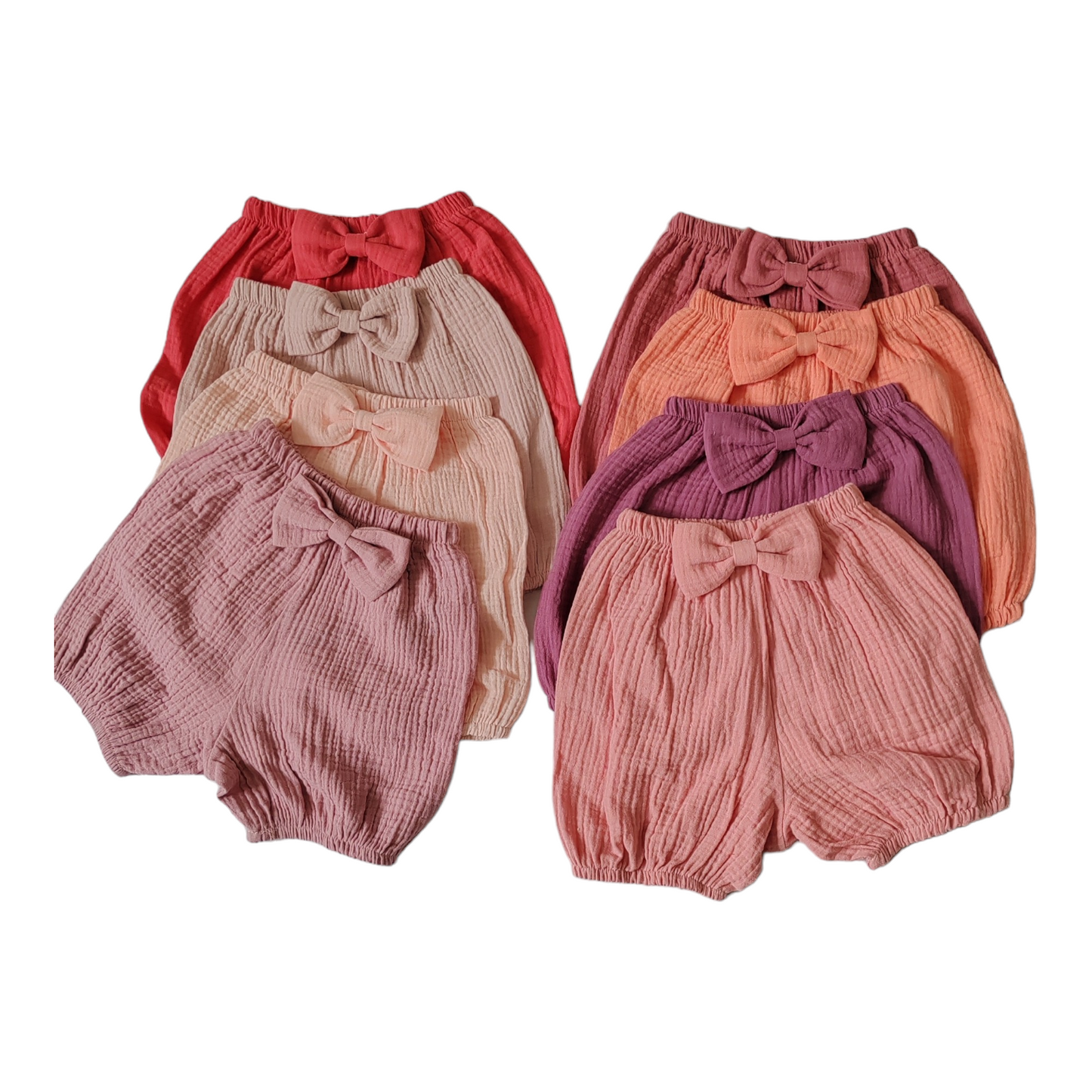 8 different shades of pink baby bloomers with a bow, crafted from soft double gauze fabric, designed for girls’ cake smash photoshoots.