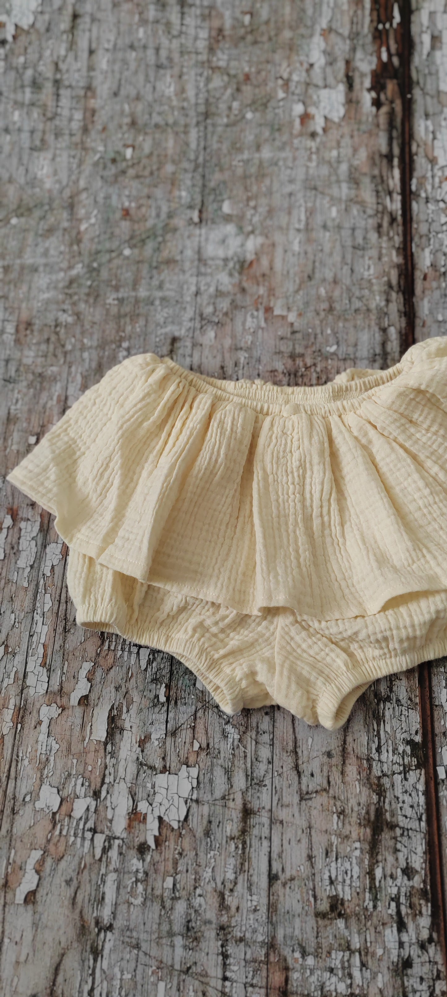Cream skirted baby bloomers laid flat, highlighting their elegant and comfortable fit