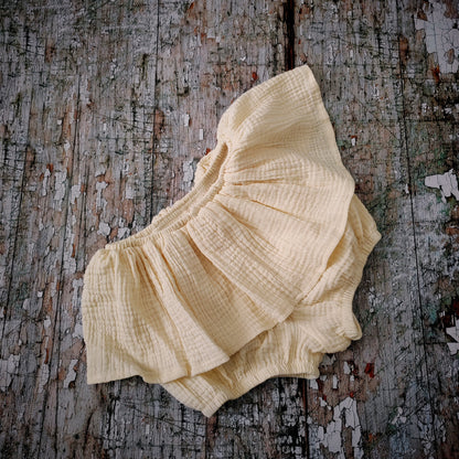 Front view of cream skirted baby bloomers, featuring soft ruffles and an elastic waistband.